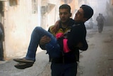 A man carries another man who was wounded during airstrikes through an alleyway.