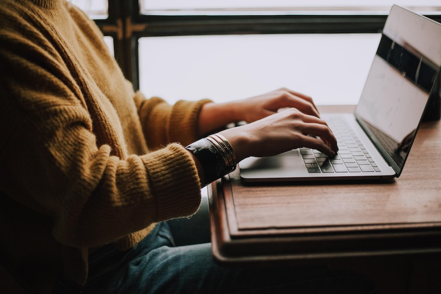 Hands using a laptop at a table