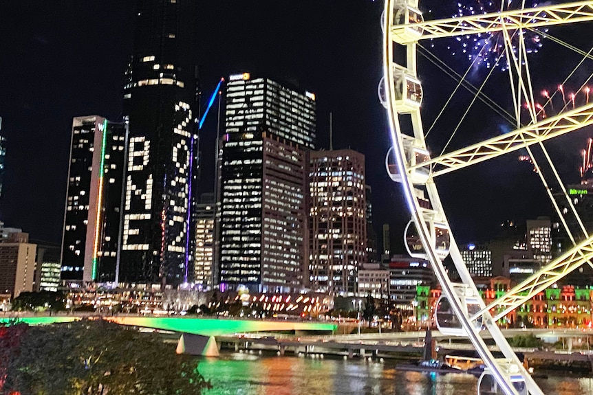 Fenêtres d'un immeuble illuminées en BNE 2032 avec un feu d'artifice dans le ciel.