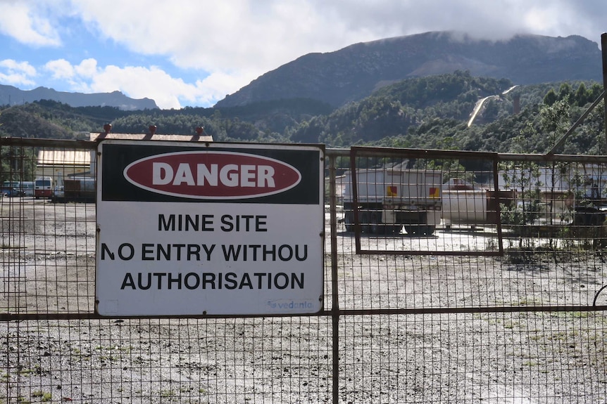 A locked gate with a sign that says "danger: mine site"
