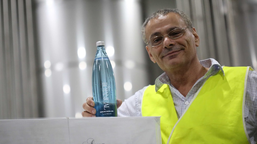 Bruce Kambouris smiles as he shows off a bottle of his water.