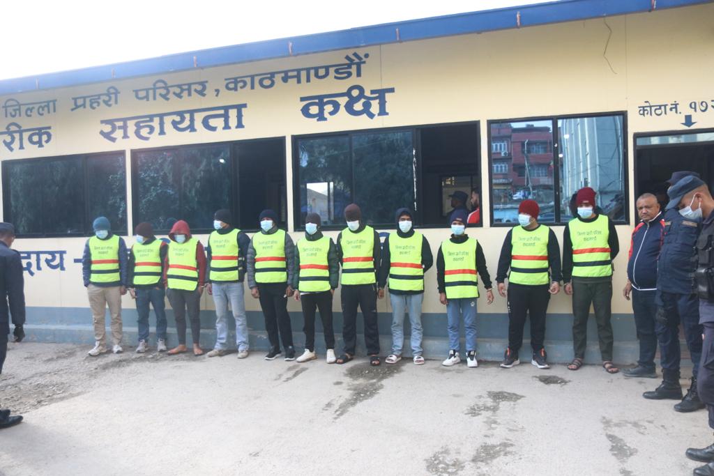 A row of people in yellow vests with their wrists bound by linking handcuffs 