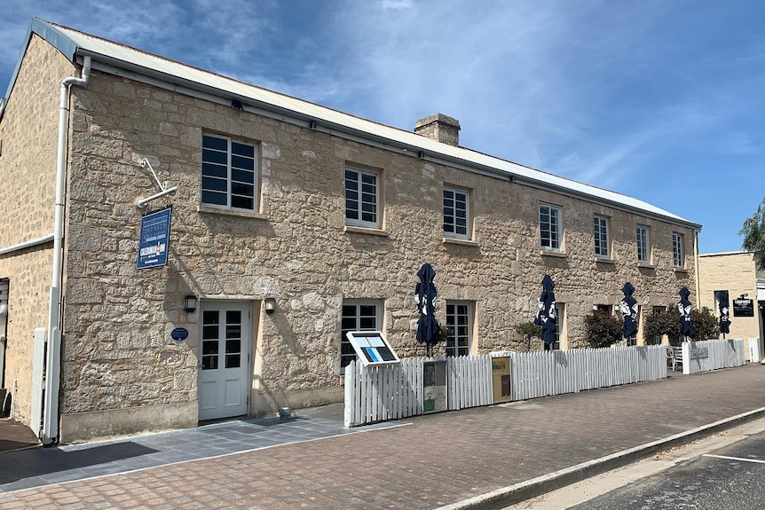 An old beige limestone building with windows and umbrellas out the front