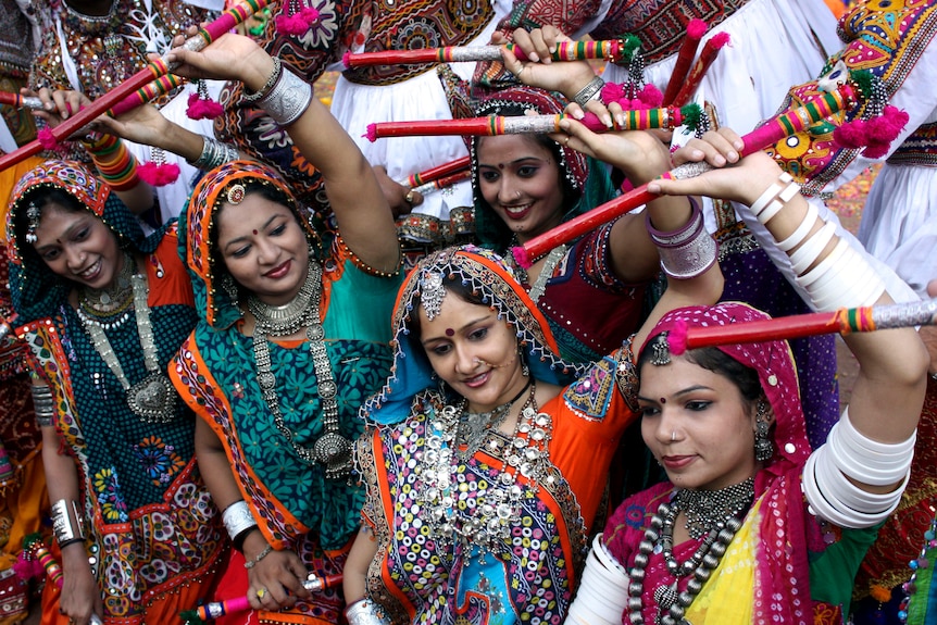 group of women wearing colorful dresses and performing a traditional Indian dance