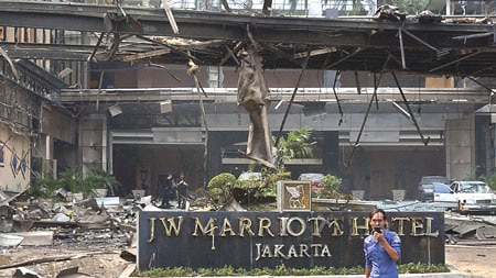 A firefighter walks past the damaged hotel