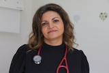 Farza Rastegar stands inside a clinic, with a stethoscope around her shoulders.