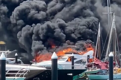 Luxury yacht on fire parked in a marina. 