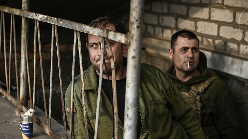 Ukrainian servicemen stand at the entrance of a basement shelter near Bakhmut.