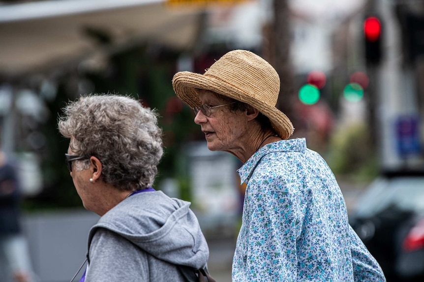 Two women walk down the street.