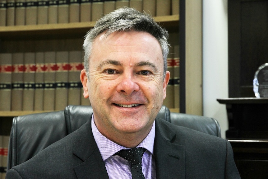 A man in a suit smiles at the camera