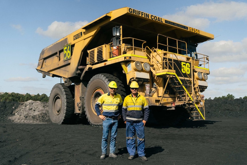 Two men stand in front of a haul truck at Griffin Coal Mine in Collie, WA.