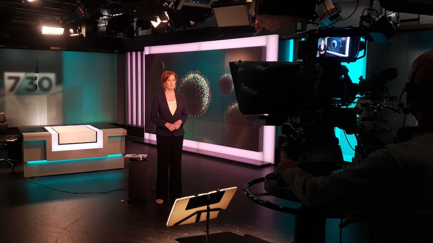 Woman standing in TV studio looking at camera.