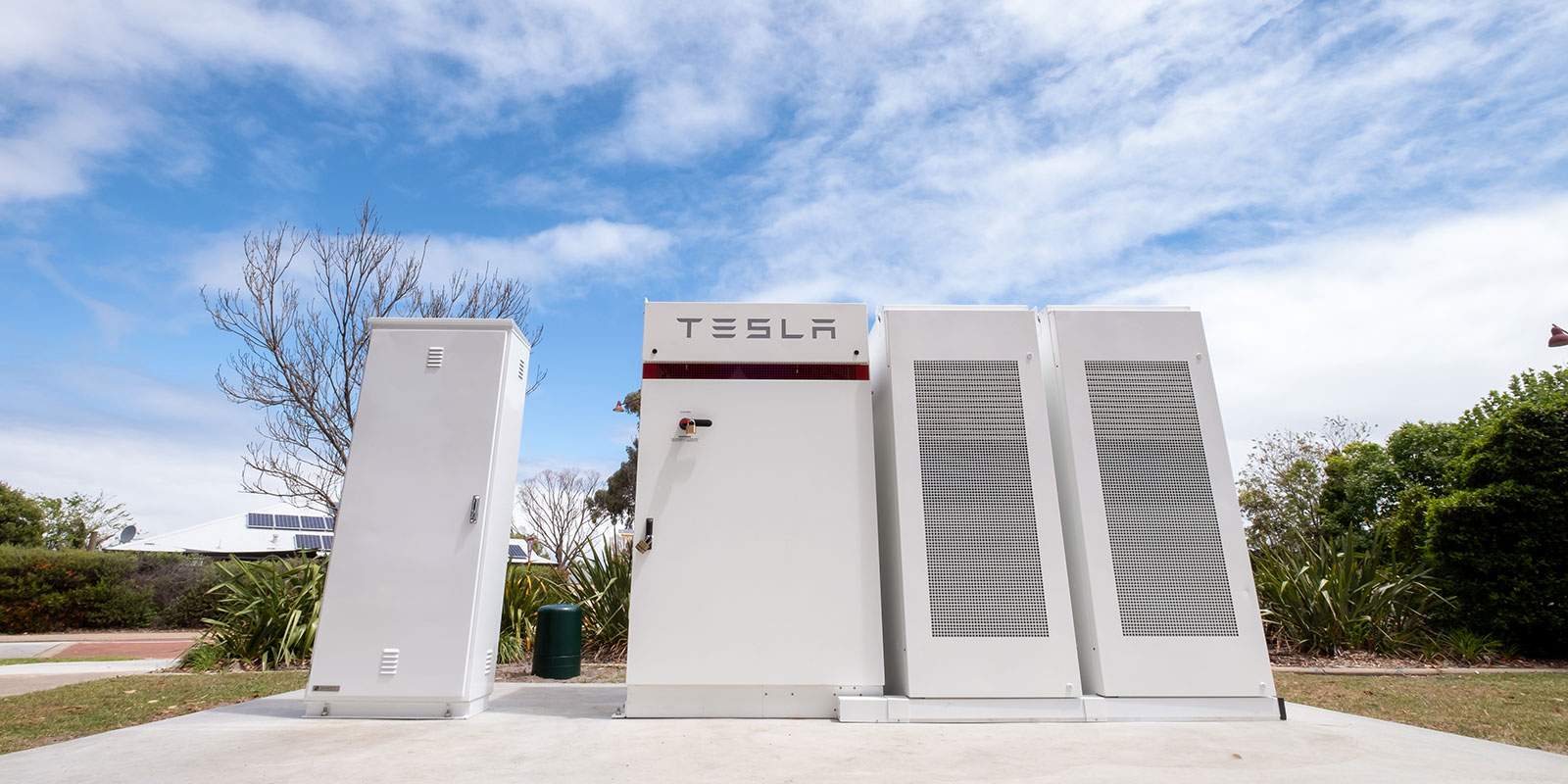A Tesla battery standing on a streetside kerb.