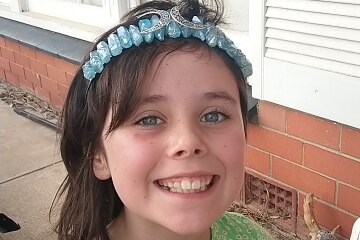 A smiling girl wearing a headband and a green shirt