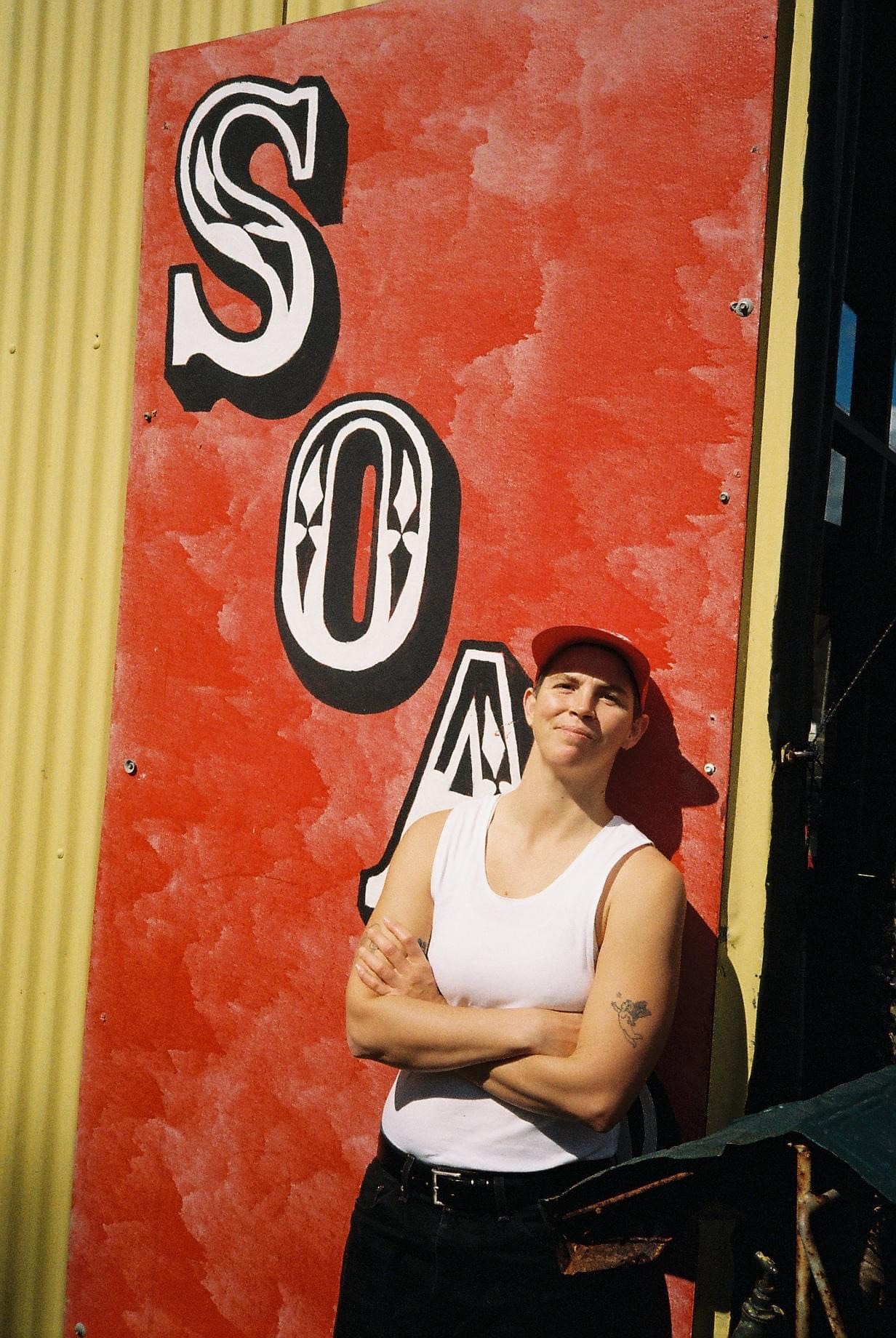 A young woman looking at the camera, holding arms. 