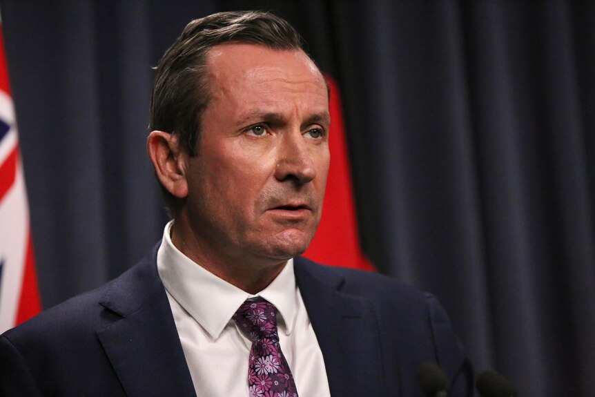 WA premier Mark McGowan stands at a lectern wearing a suit and tie.