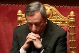 Italian Premier Mario Draghi sits on a gold chair looking pensive