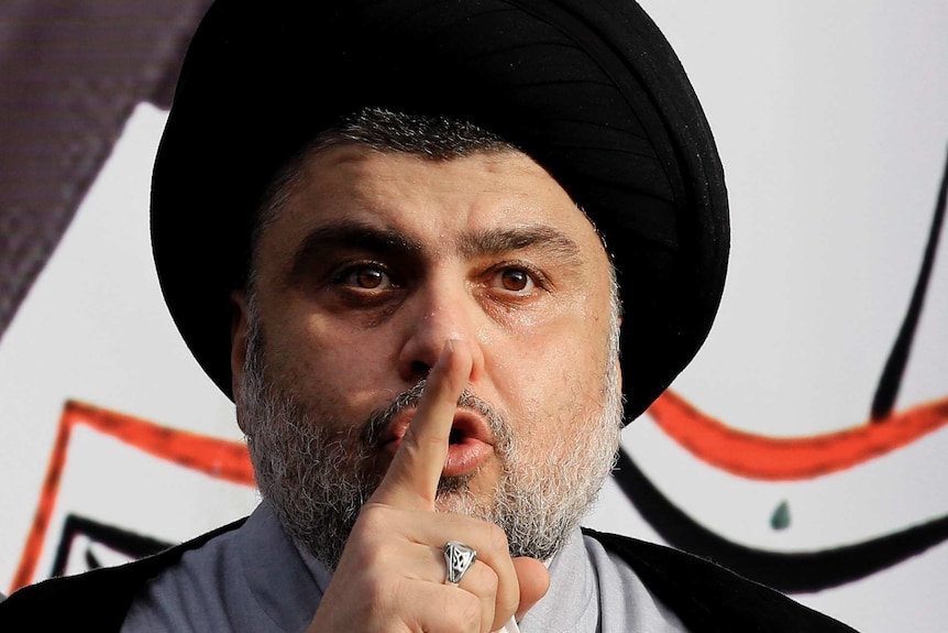 Moqtada al-Sadr holds one finger up to his lips during a speech