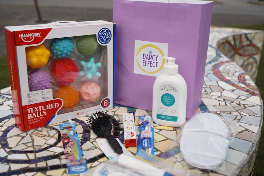 Contents of a gift bag, including basic toiletries like face wash, toothbrush and toothpaste.