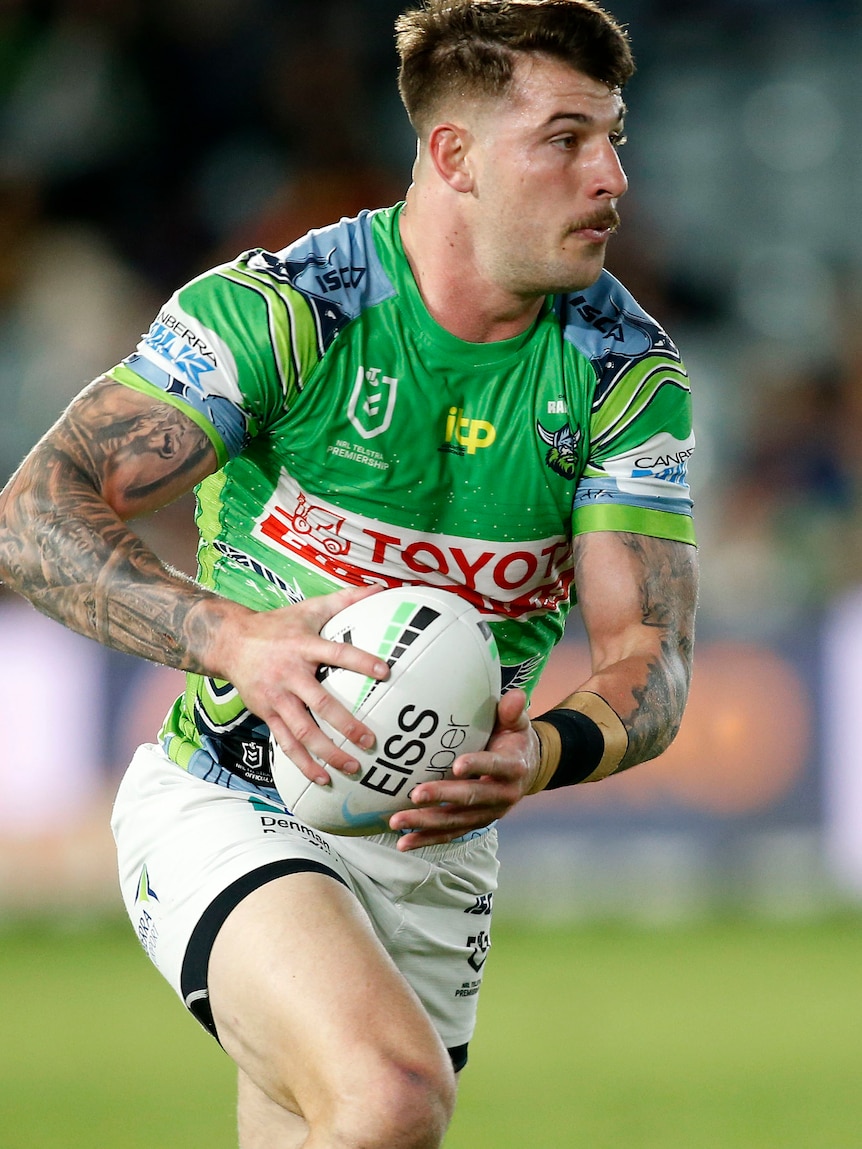 Curtis Scott running with a ball in a Canberra Raiders jersey.