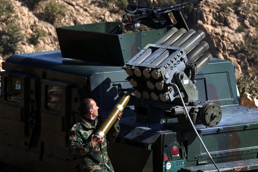 A Kurdish fighter loads a heavy artillery weapon.
