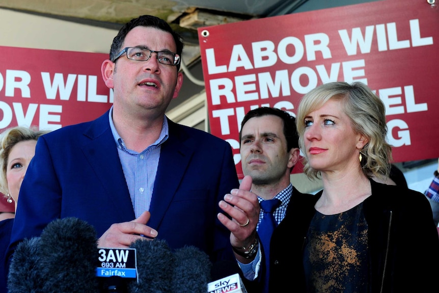 Daniel Andrews speaks to reporters in front of Labor campaign banners.