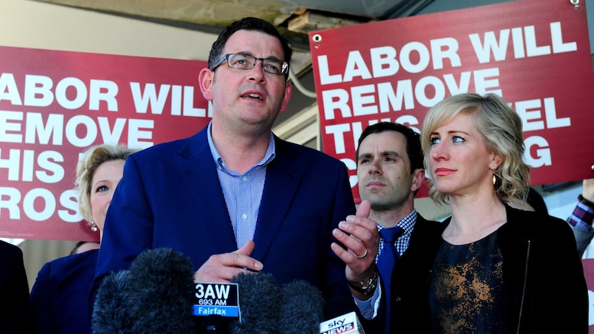 Daniel Andrews speaks to reporters in front of Labor campaign banners.