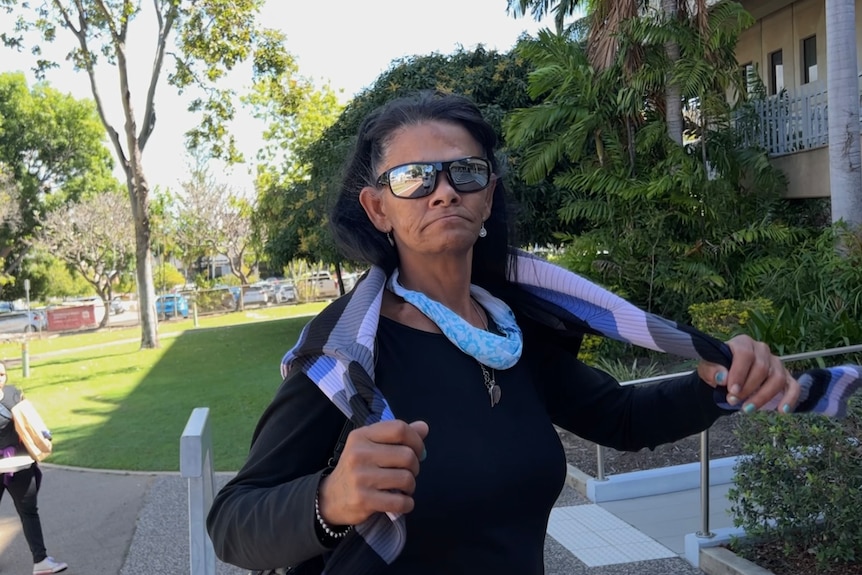 Leanne Eatts walks past a camera wearing reflective sunglasses.