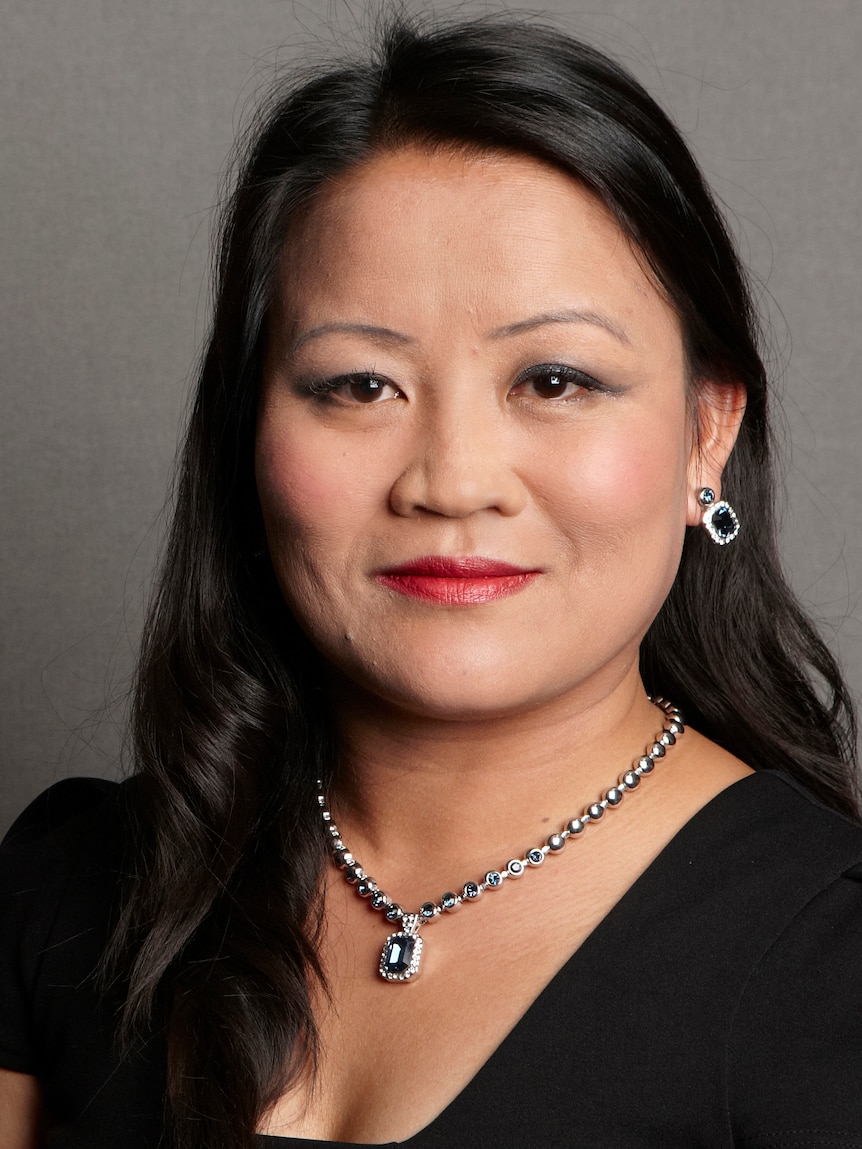 A headshot of a woman of Asian appearance in black outfit. 