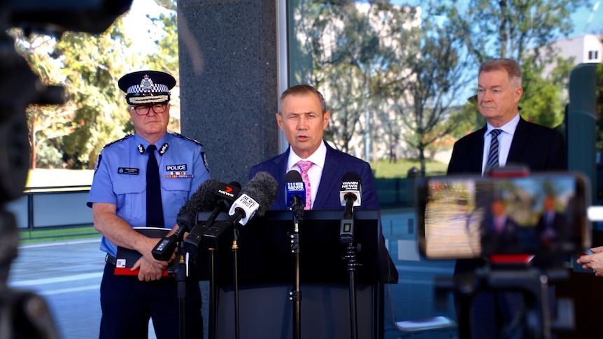 Three men flanked by microphones