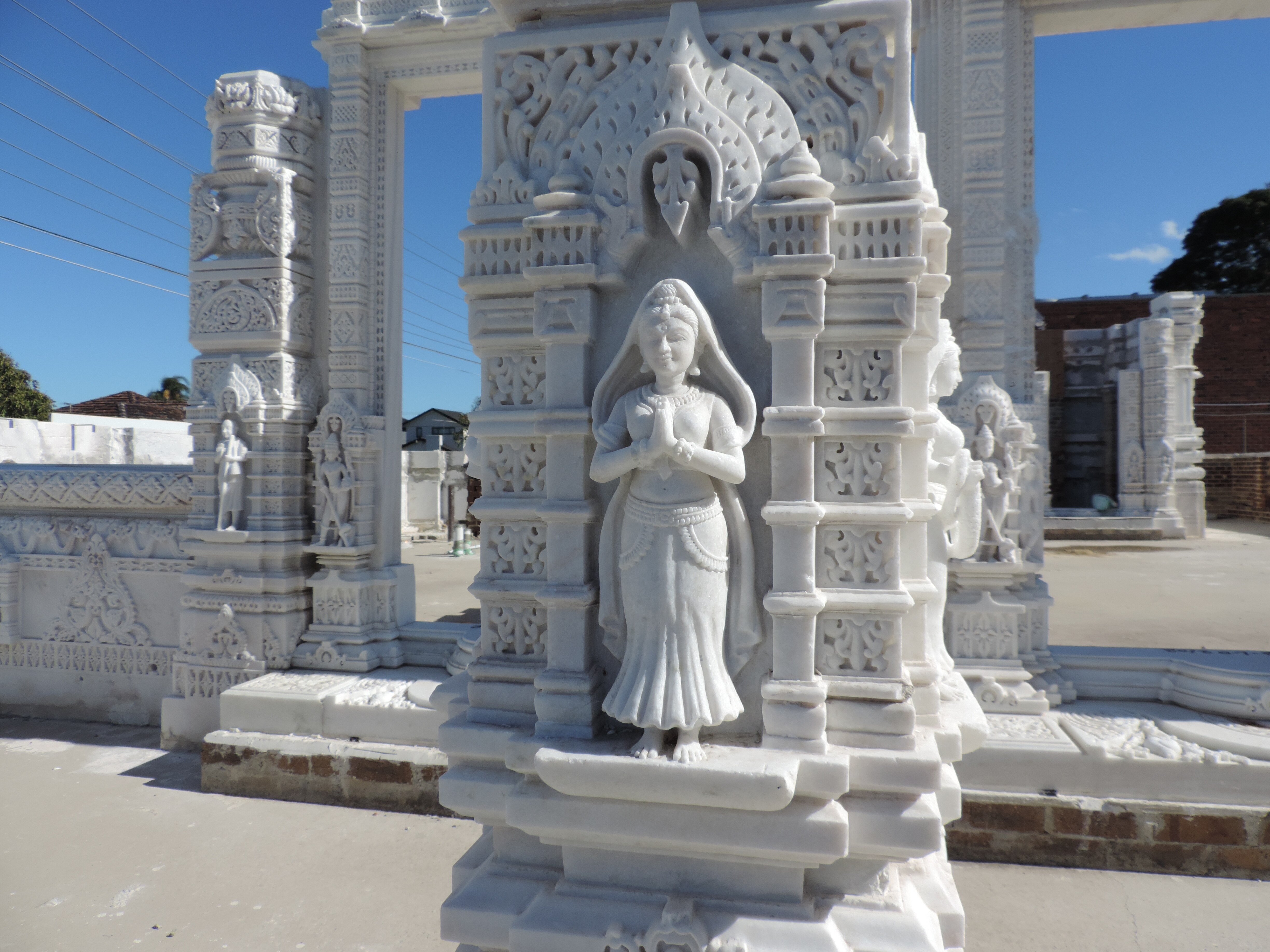 Close-up of a white marble statue of a woman with folded hands, carved into a temple pillar