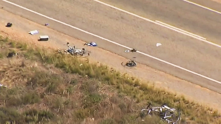 Damaged bicycles lie by the side of the road