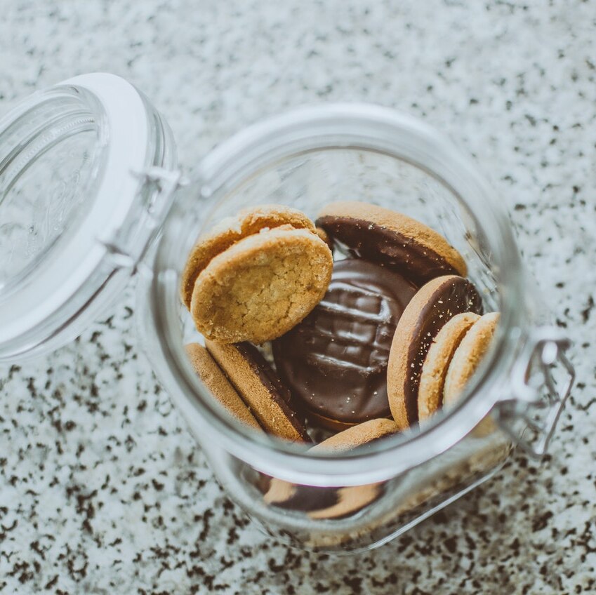A half-empty glass jar of chocolate biscuits, opened and pictured from above.