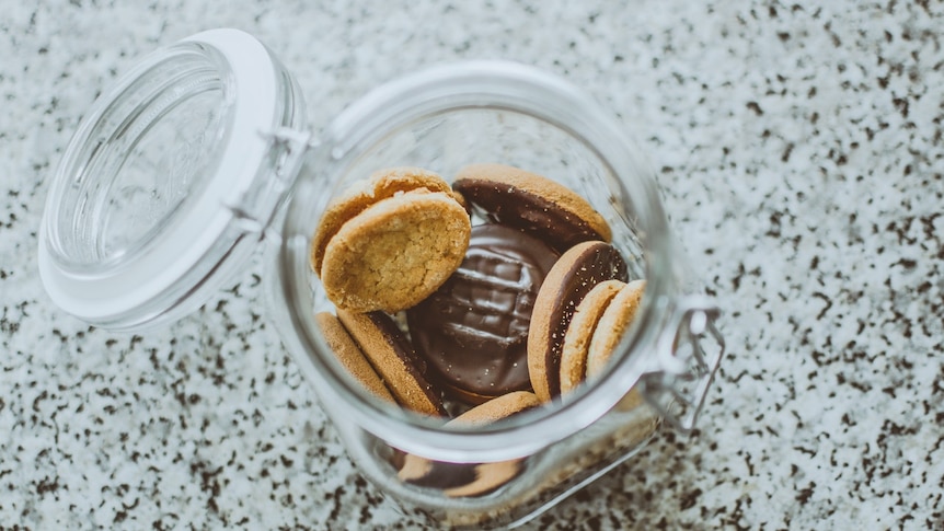 A half-empty glass jar of chocolate biscuits, opened and pictured from above.