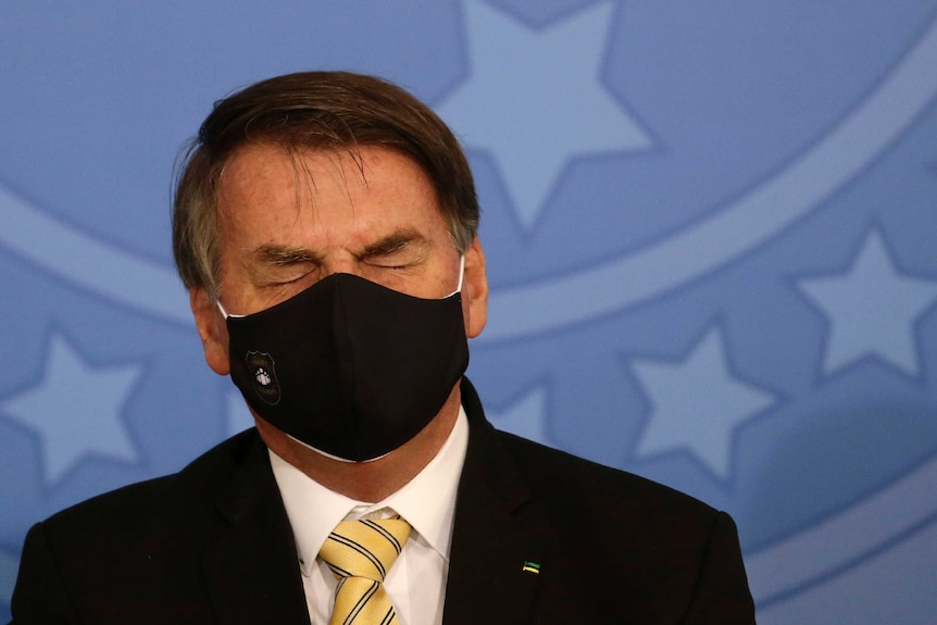 Jair Bolsonaro wearing a black face mask with his eyes closed.