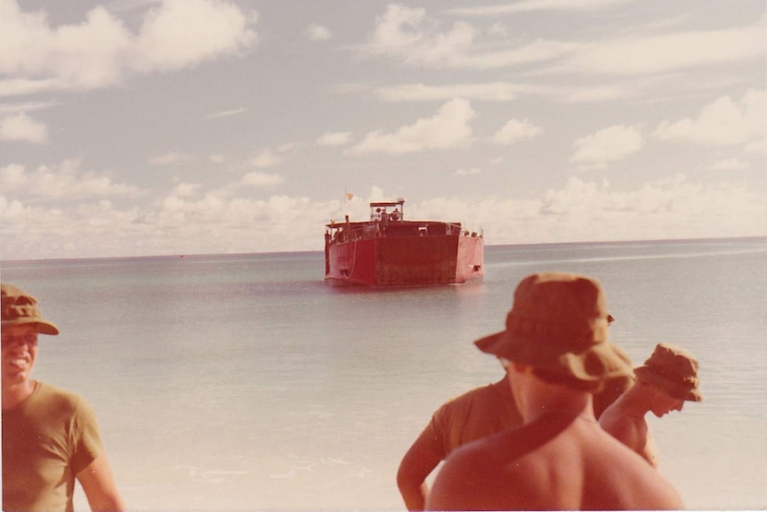 Soldiers stand on Enetewak as comrades arrive by boat.