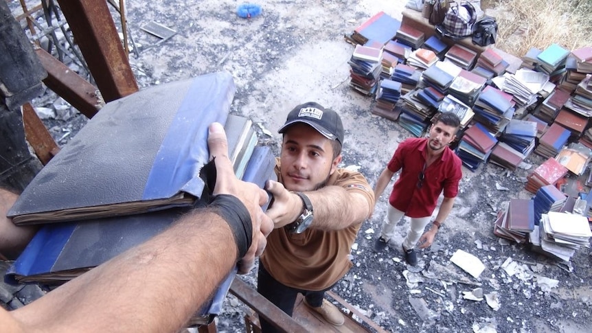 Volunteers help carry out books from the Mosul library destroyed by Islamic State.