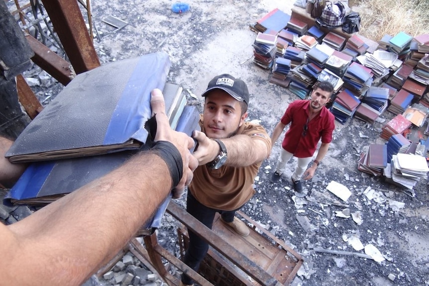 Volunteers help carry out books from the Mosul library destroyed by Islamic State.