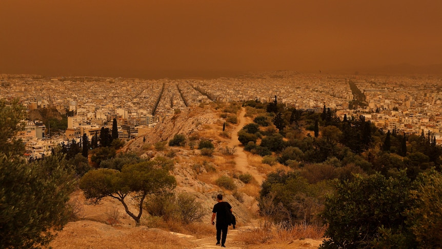 A wide shot of the city of Athens that is covered in orange dust.