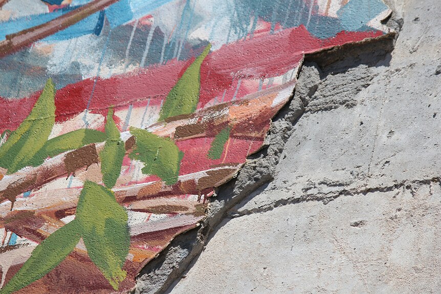 Detail of damaged mural showing paint and concrete