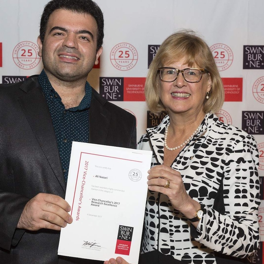 Two adults stand smiling holding a certificate.