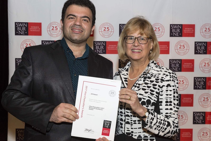 Two adults stand smiling holding a certificate.