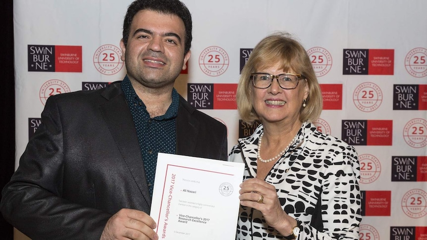 Two adults stand smiling holding a certificate.