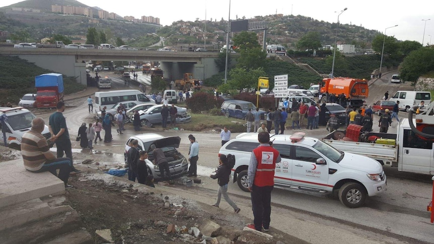 Rescue workers and people are tending to broken down cars on streets after flooding in Ankara.
