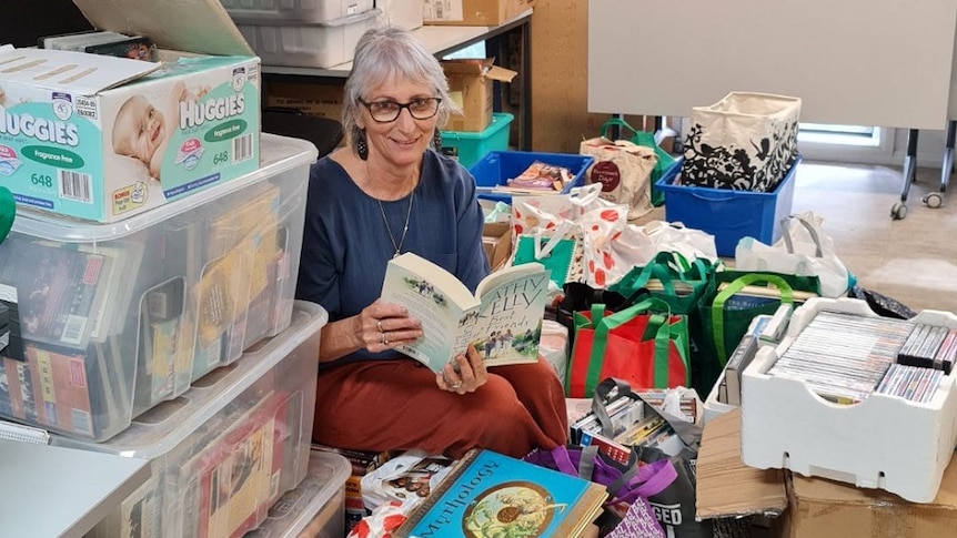 Sue Reynolds from Rotary Club of Griffith Avanti sits among many bags of donated books to be sent to Lismore's library