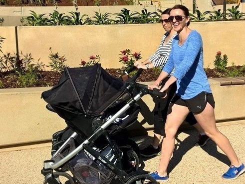 Two women walking with prams walking along pathway at tiered steps and ramps.