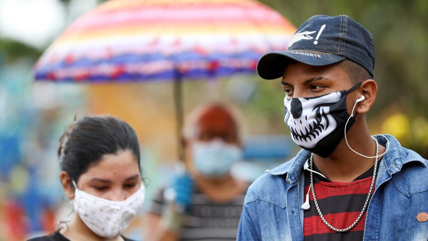 A young man and woman wear face masks at a funeral