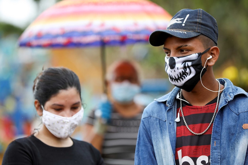 A young man and woman wear face masks at a funeral