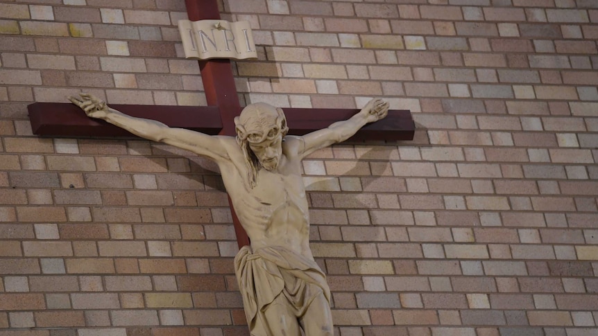 A crucifix is affixed to a brick wall at St Christopher's cathedral in Canberra