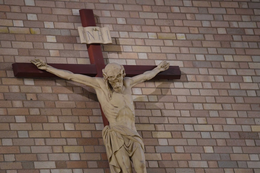 A crucifix is affixed to a brick wall at St Christopher's cathedral in Canberra